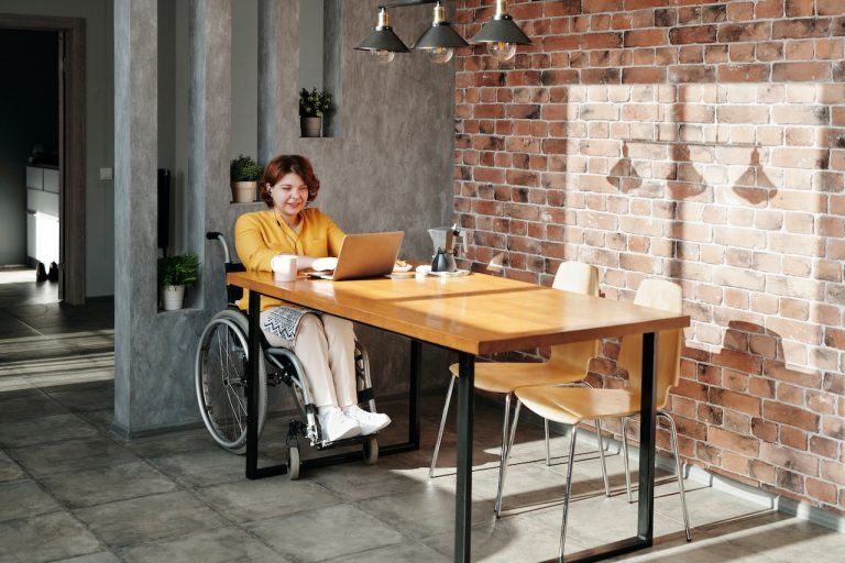A woman in a wheelchair looking up designing a disability-friendly home on a laptop
